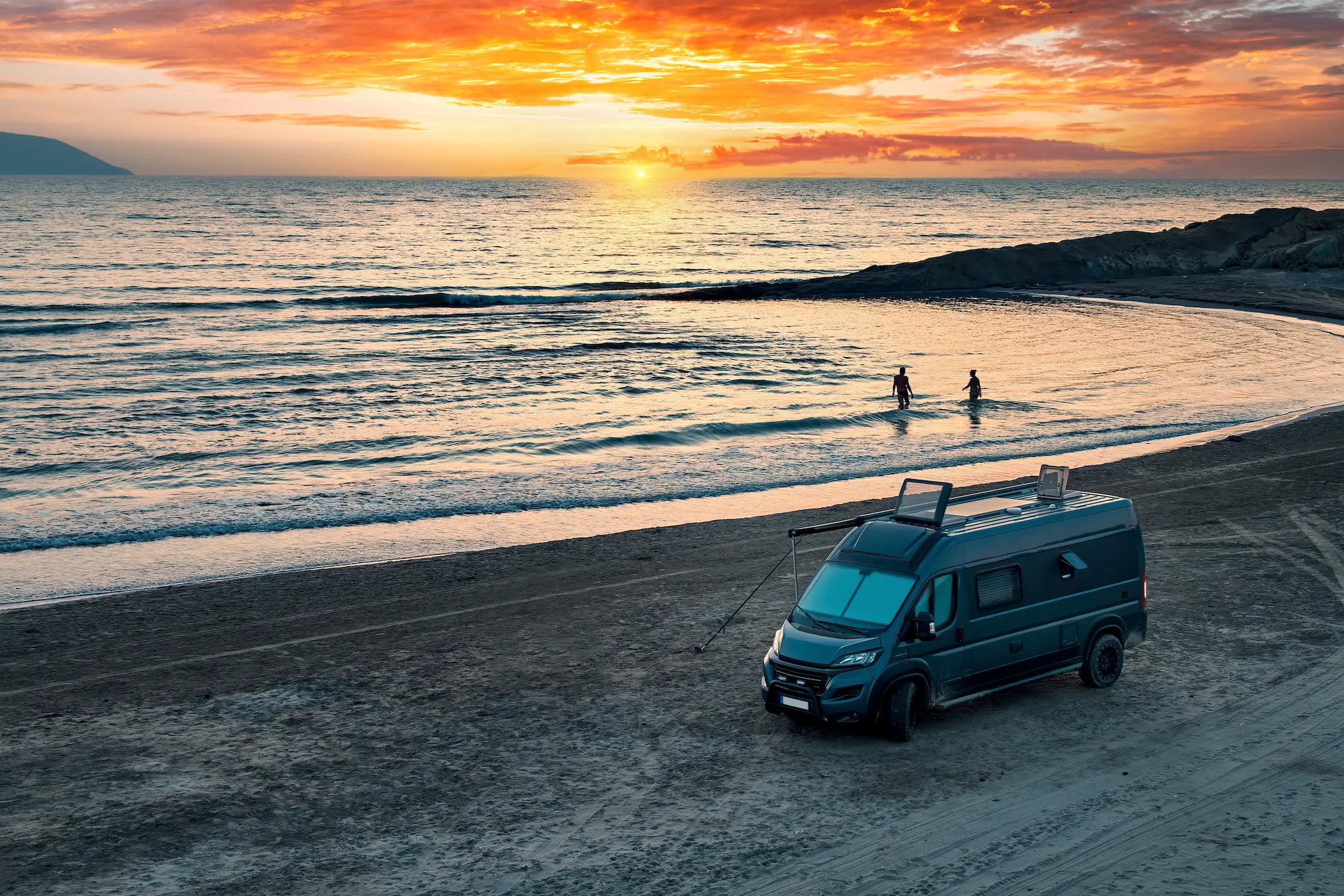 Camper steht am Strand, Sonnenuntergang spiegelt sich im Wasser – Roadfun Wohnmobil für unvergessliche Roadtrips.